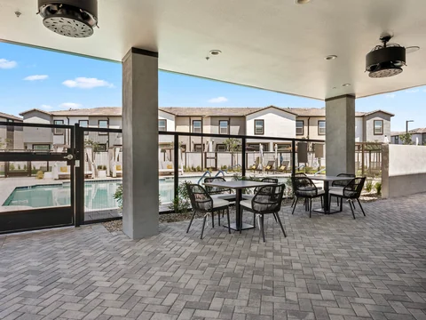 Covered patio with dining tables, ceiling fans, and a view of the pool