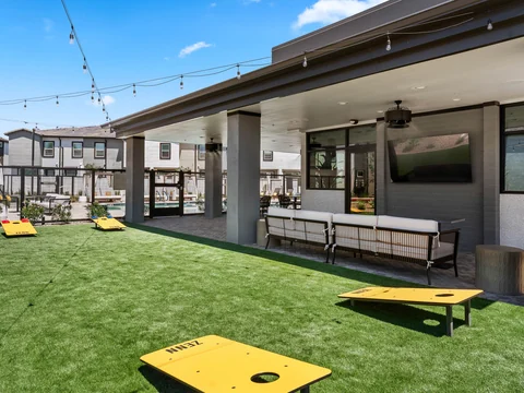 Cornhole boards on the clubhouse lawn beneath string lights