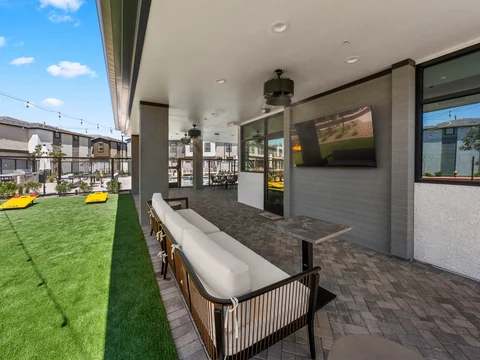 Long cushioned sofa and outdoor television beside the game lawn