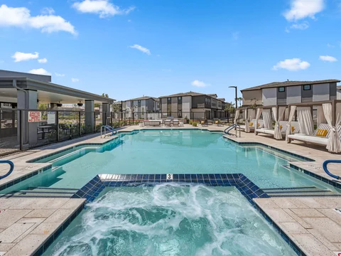 Bubbling hot tub and resort-style pool with shaded cabanas