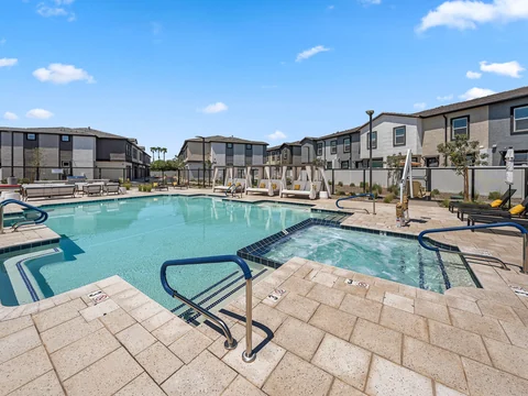 Wide view of the pool and hot tub with cabanas along the deck