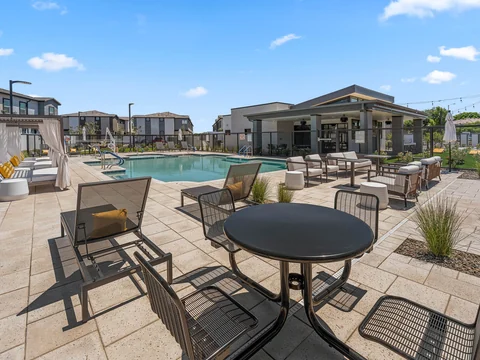 Poolside dining tables and lounge seating facing the clubhouse
