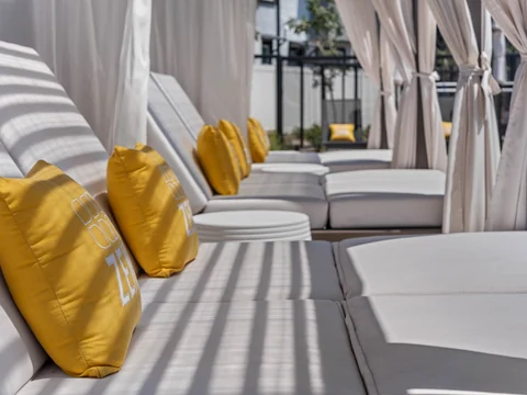 Close-up of striped cabana cushions and yellow Zenn pillows