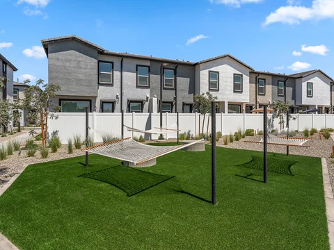 Hammocks over a green lawn surrounded by townhomes and desert landscaping