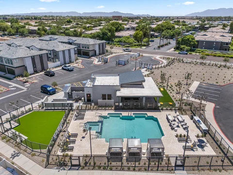 Aerial view across the pool and clubhouse toward the neighborhood and distant mountains