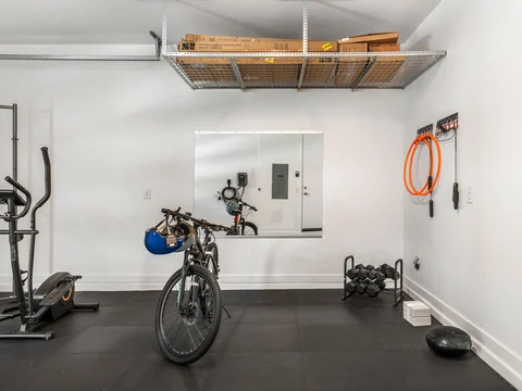 Garage with exercise equipment, a bicycle, and an overhead storage rack