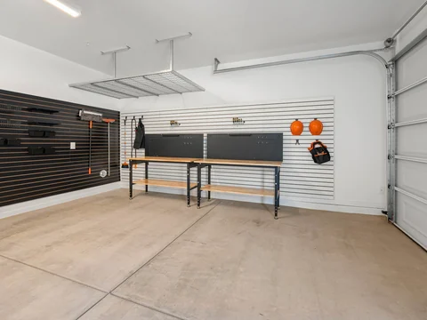Wide garage interior with workbenches and wall storage