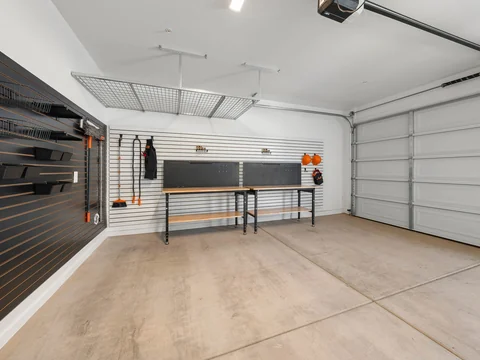 Garage with open floor space, workbenches, and overhead storage
