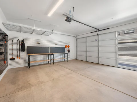 Attached two-car garage with a workbench and overhead storage rack