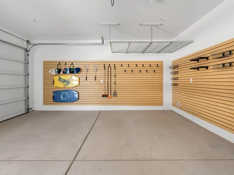 Garage with overhead storage and a wood slat wall holding outdoor gear