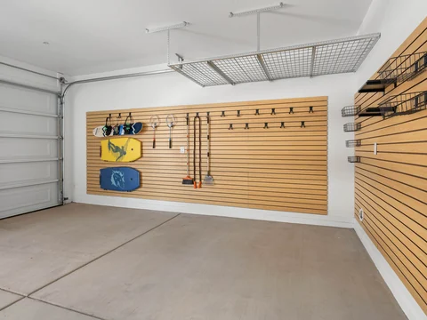 Ceiling-mounted garage storage rack above a wall of outdoor gear