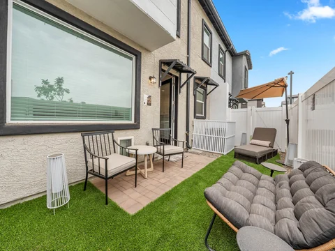 Private fenced yard with green turf and furnished patio seating