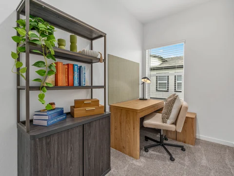 Home office with a wood desk, upholstered chair, and bookcase