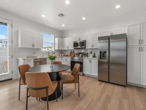 Round dining table beside a white kitchen with stainless-steel appliances