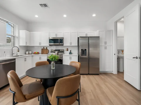 White kitchen and round dining table with warm upholstered chairs