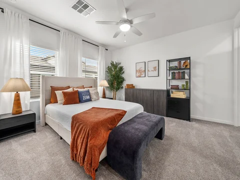 Bedroom with a rust-colored duvet, dark upholstered bed, and window seating