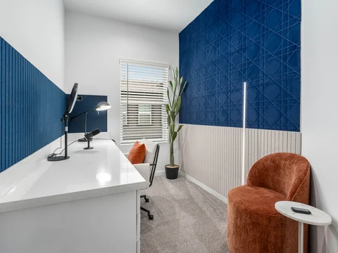 Home office with a white desk, blue accent walls, and a rust-colored chair
