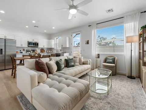 Open living room with tufted sofas looking toward the dining area and kitchen