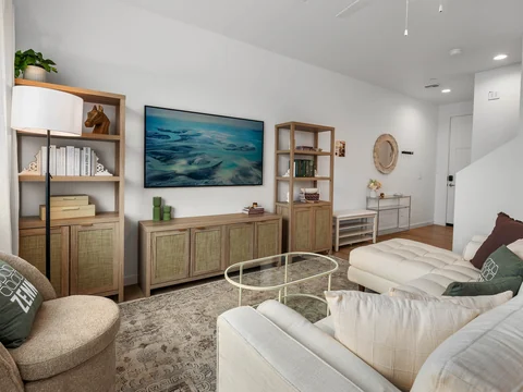 Living room with tufted sofas, a green media console, and framed artwork