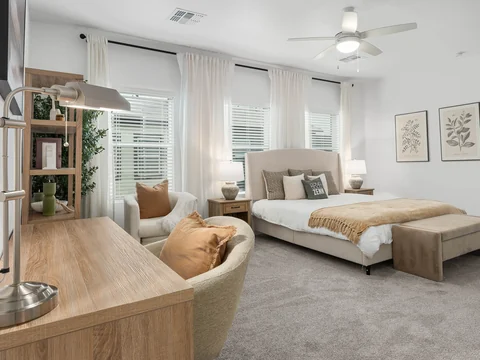 Bedroom with a wood desk and a cushioned reading chair beside the bed